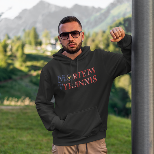 Man wearing a black hoodie with text, standing outdoors with mountains in the background